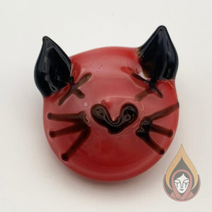 Glass pendant shaped like a red cat face with X's for eyes. It has black ears, whiskers and a heart shaped nose. 
